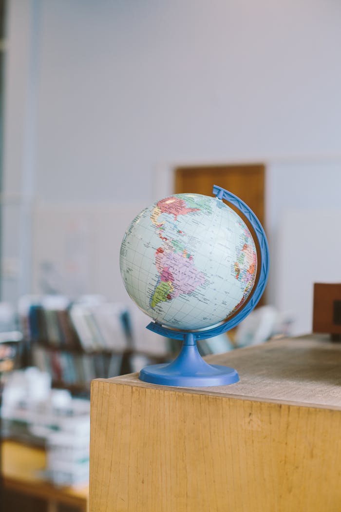 A globe on a wooden shelf in a library environment, ideal for educational themes.